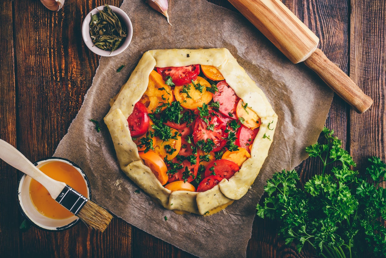 Uncooked tomato galette on baking paper. View from above