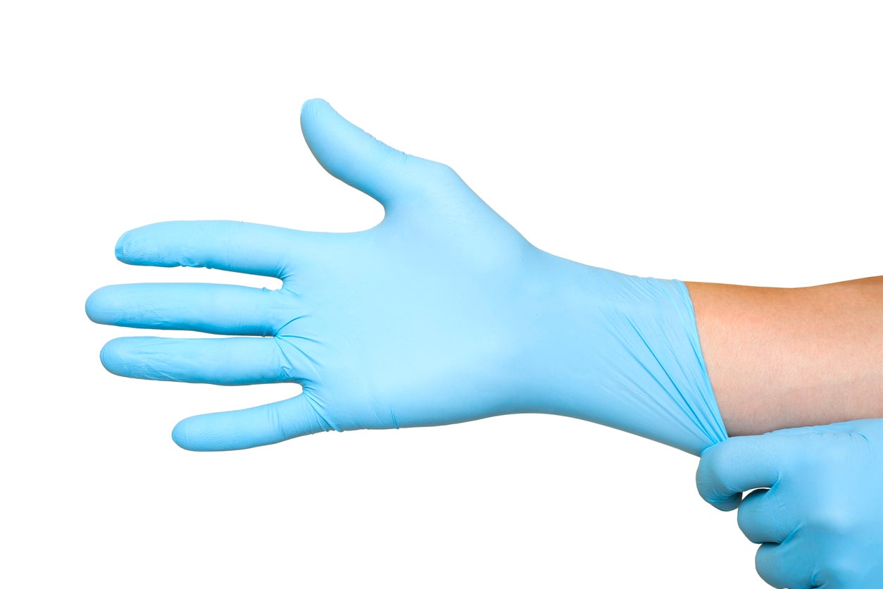 Doctor putting on protective blue gloves isolated on white background