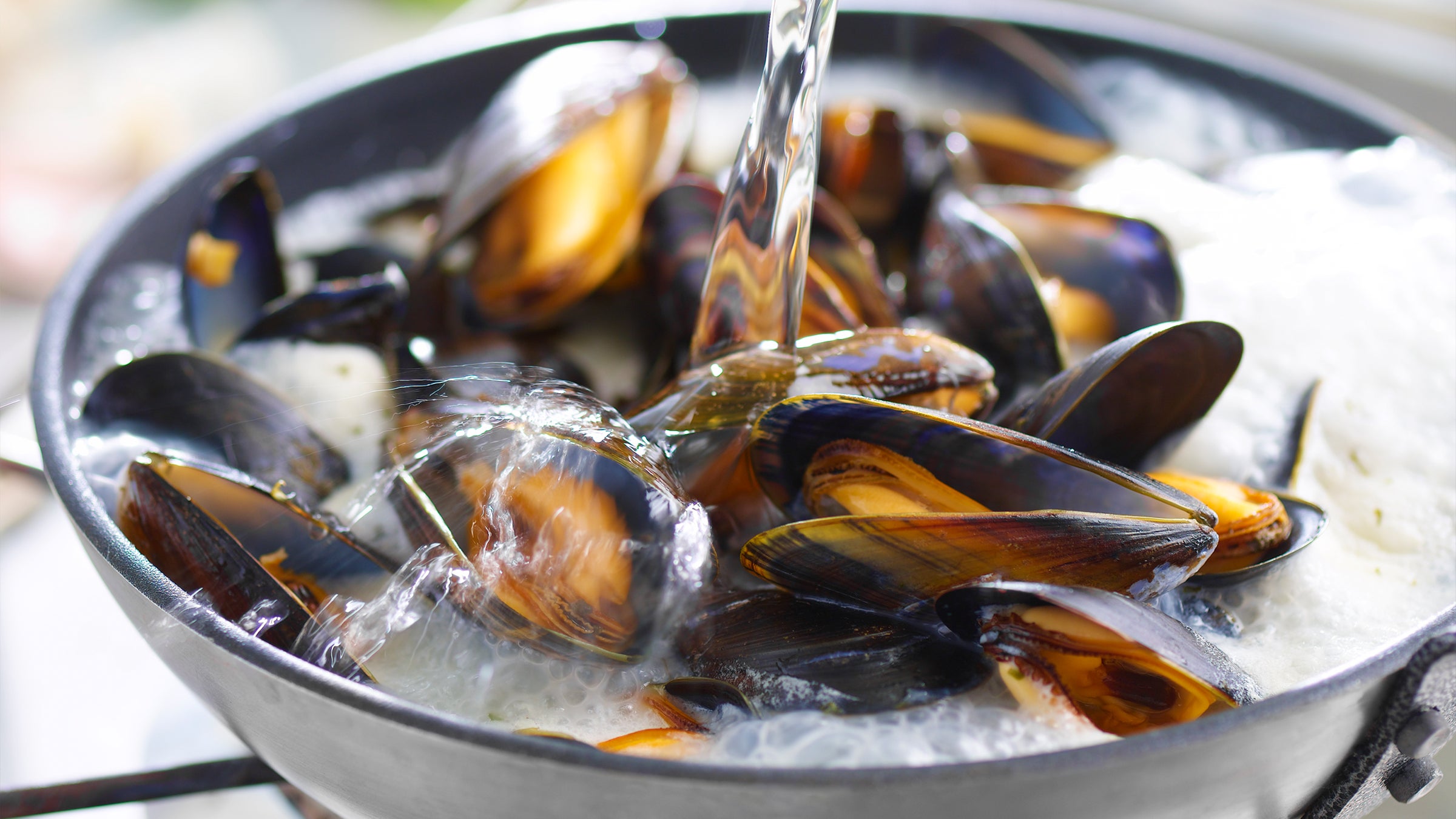 Close up on a bowl of mussels under running water.