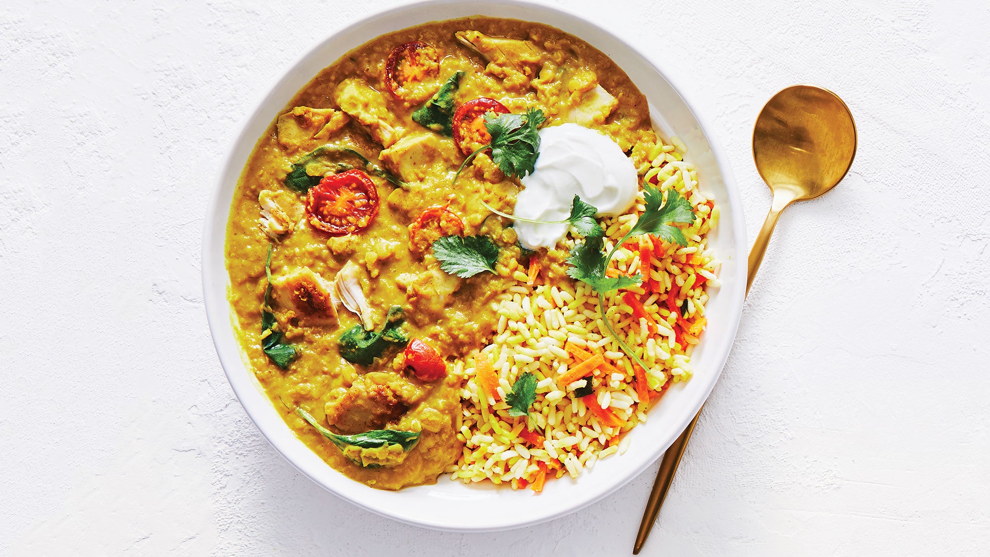 Coconut chicken and lentil curry in a bowl with gold spoon