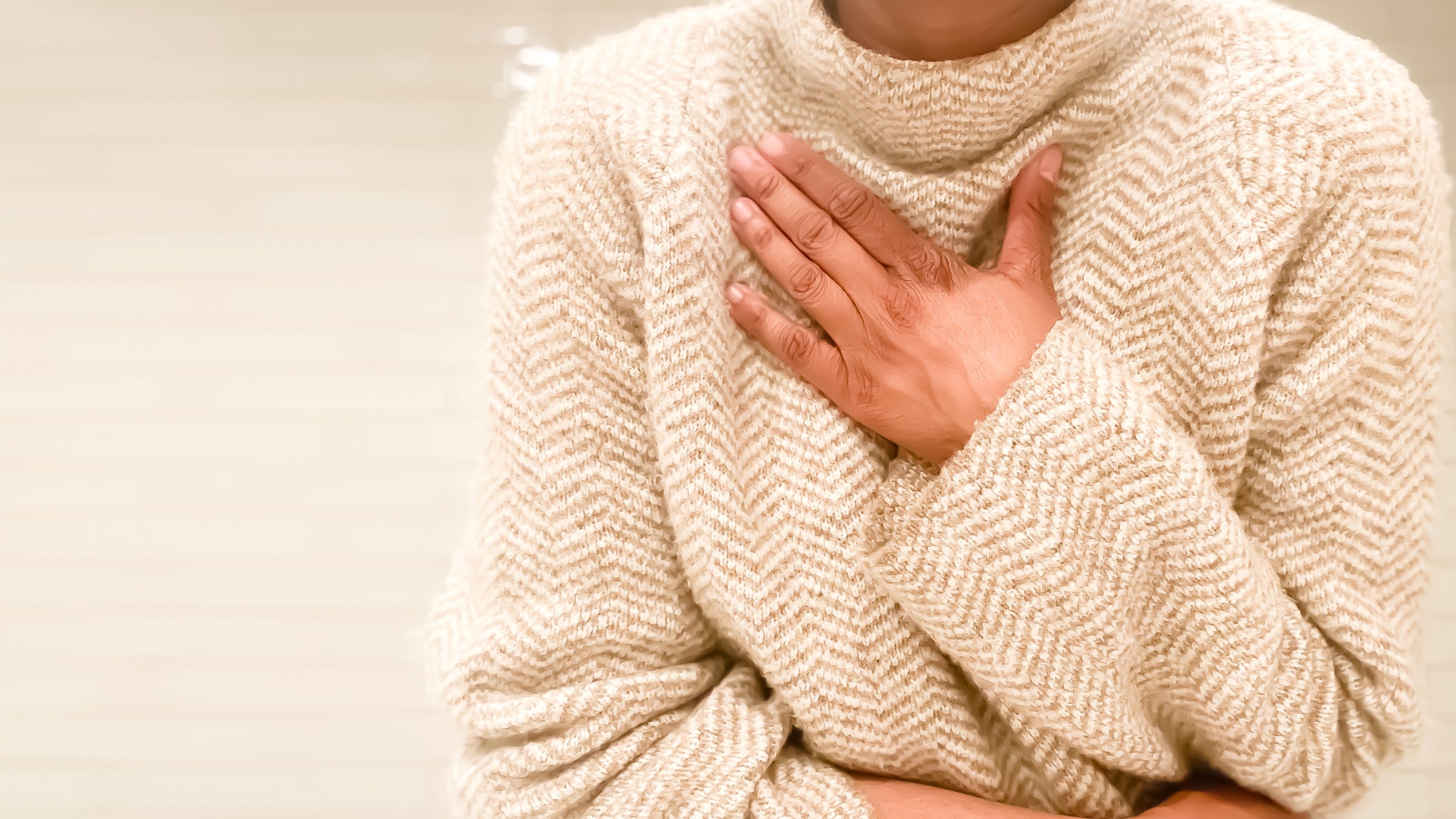 Woman in a sweater holding a hand to her chest